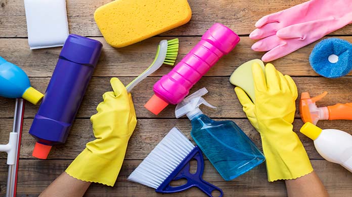 Rubber gloved hands surrounded by many cleaning supplies