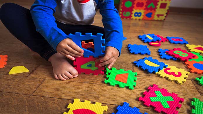 A child playing with foam squares on the floor