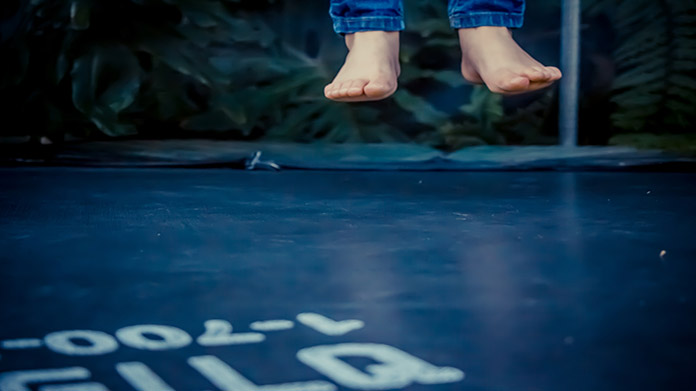 Feet suspended in air above a trampoline surface