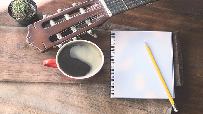 notepad and pencil with a guitar and cup of coffee on a table