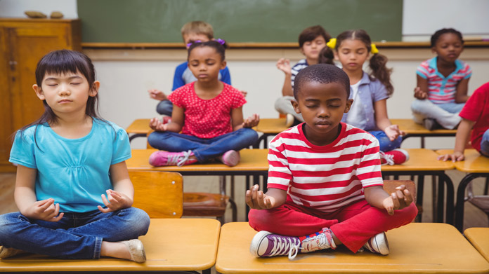Children sitting in lotus position on their school desks