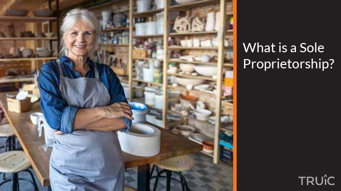 A confident sole proprietor stands in the forefront of her art studio.